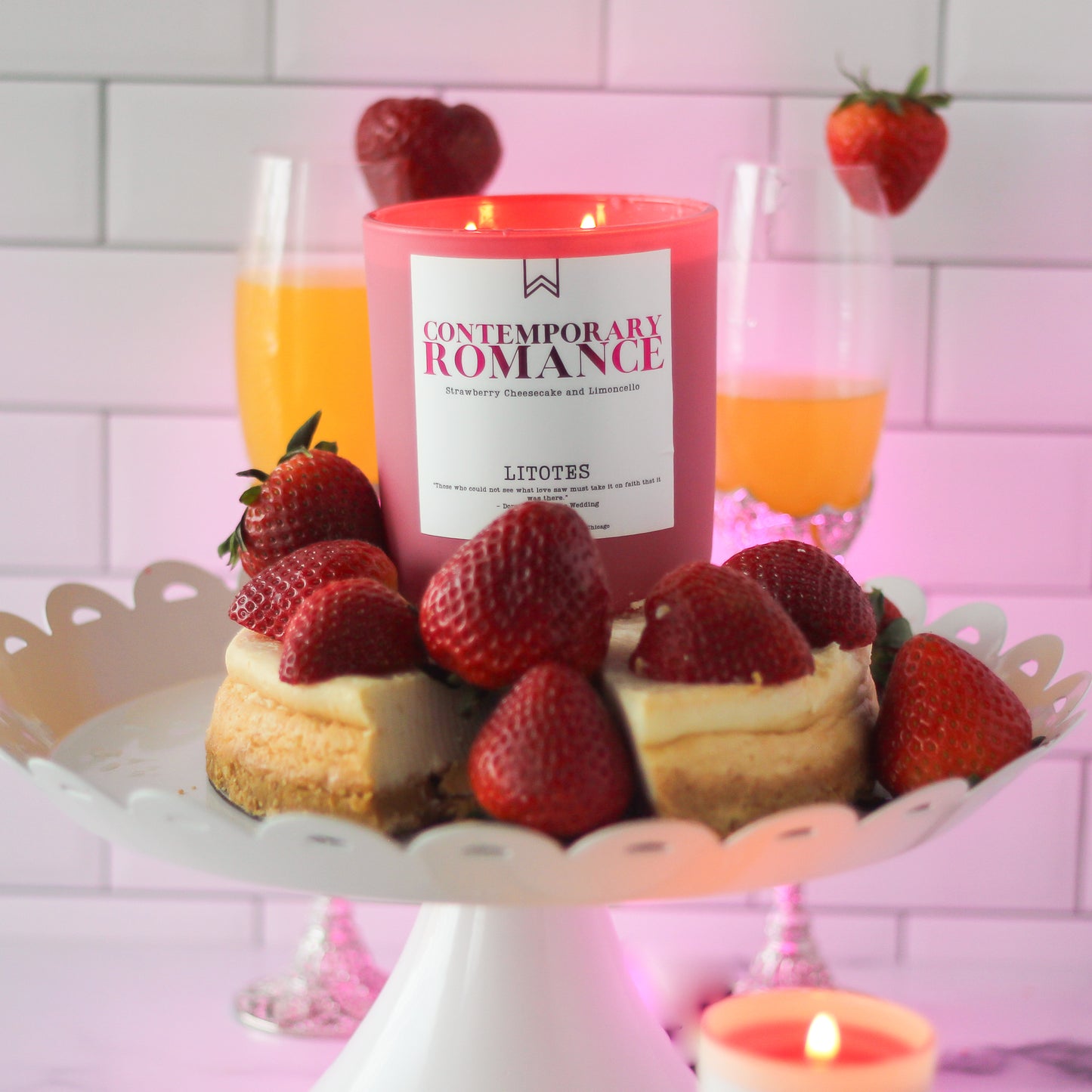 Candle labeled 'Contemporary Romance' with strawberries and pastries on a stand against a tiled wall.