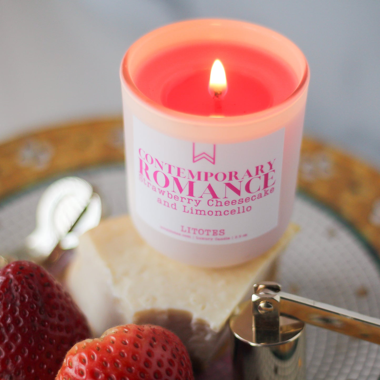 Candle labeled 'Contemporary Romance' with strawberries and a slice of cake on a plate.