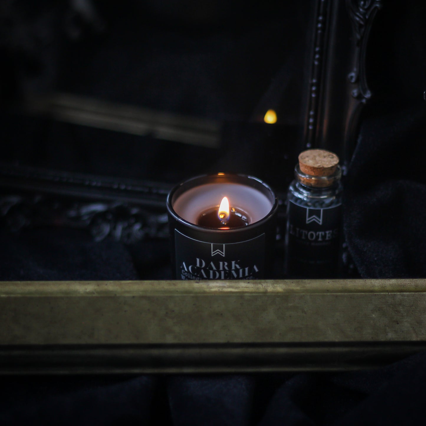 Candle labeled 'Dark Academia' and a small bottle on a dark surface