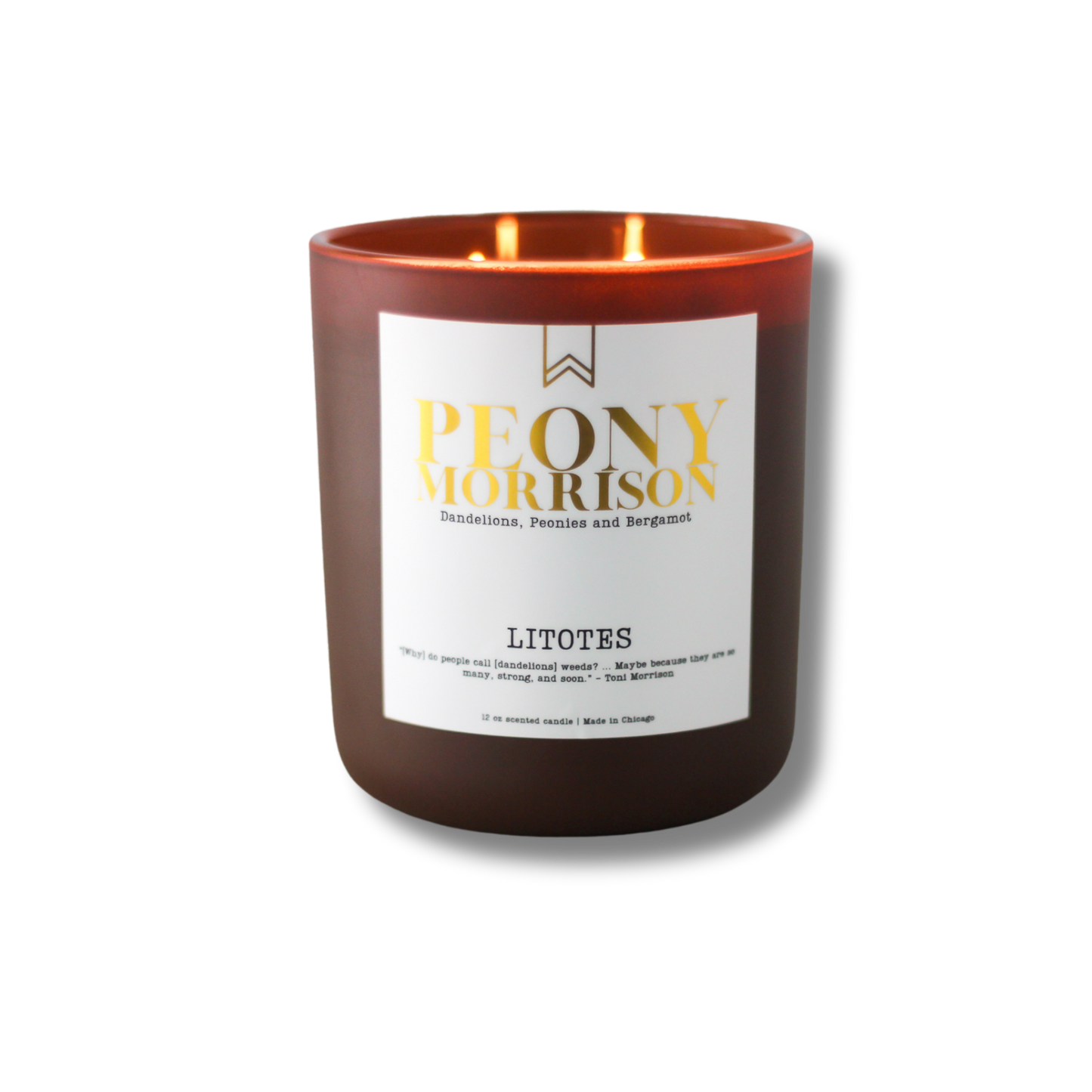 A soy wax candle with a label that reads 'Peony Morrison', with a lit flame inside a dark glass jar.